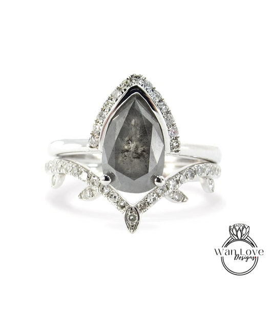 A silver ring with a large, dark gray diamond as the centerpiece, surrounded by smaller diamonds and a leaf-shaped accent.