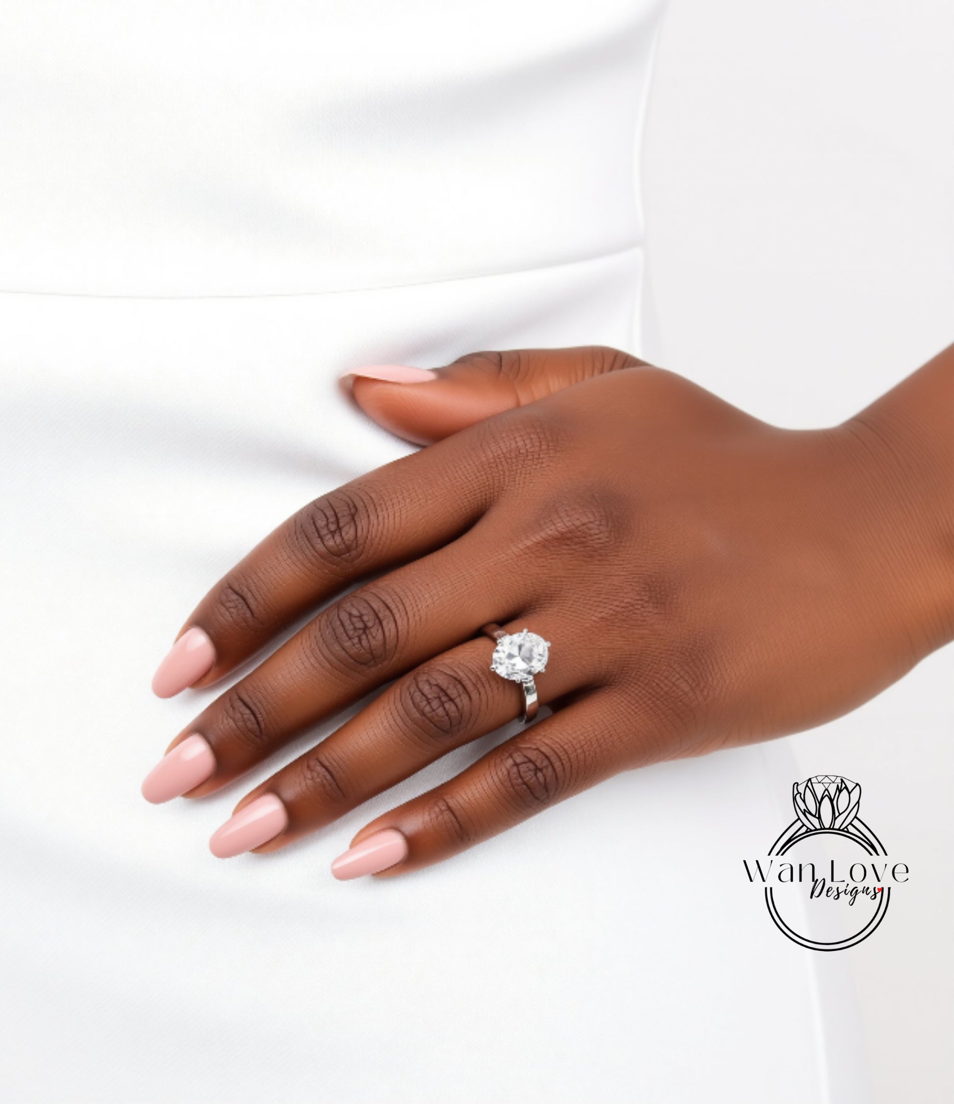 A close-up of a hand wearing a diamond engagement ring, with a white dress visible in the background.