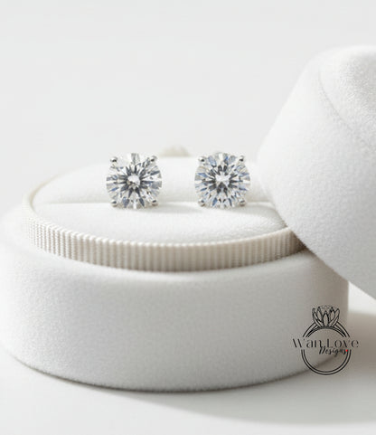 A pair of elegant diamond earrings displayed in a white velvet box, with a logo for "WanLove Designs" visible in the bottom right corner.