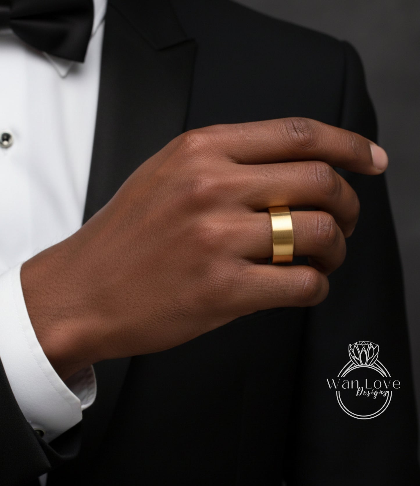 A close-up of a person's hand wearing a gold ring, with a black suit jacket visible.