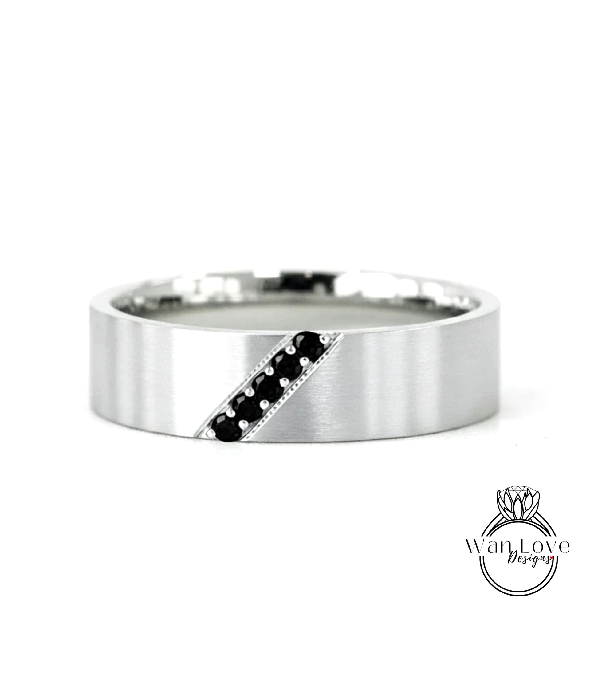 A silver-colored ring with a diagonal line through it, featuring small black stones or diamonds.