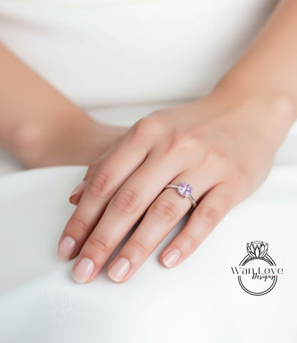 A close-up of a hand wearing a ring with a purple gemstone.