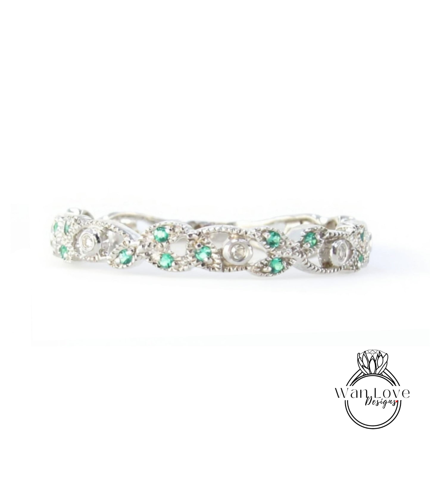 A silver ring adorned with green gemstones, including diamonds, is displayed against a white background.