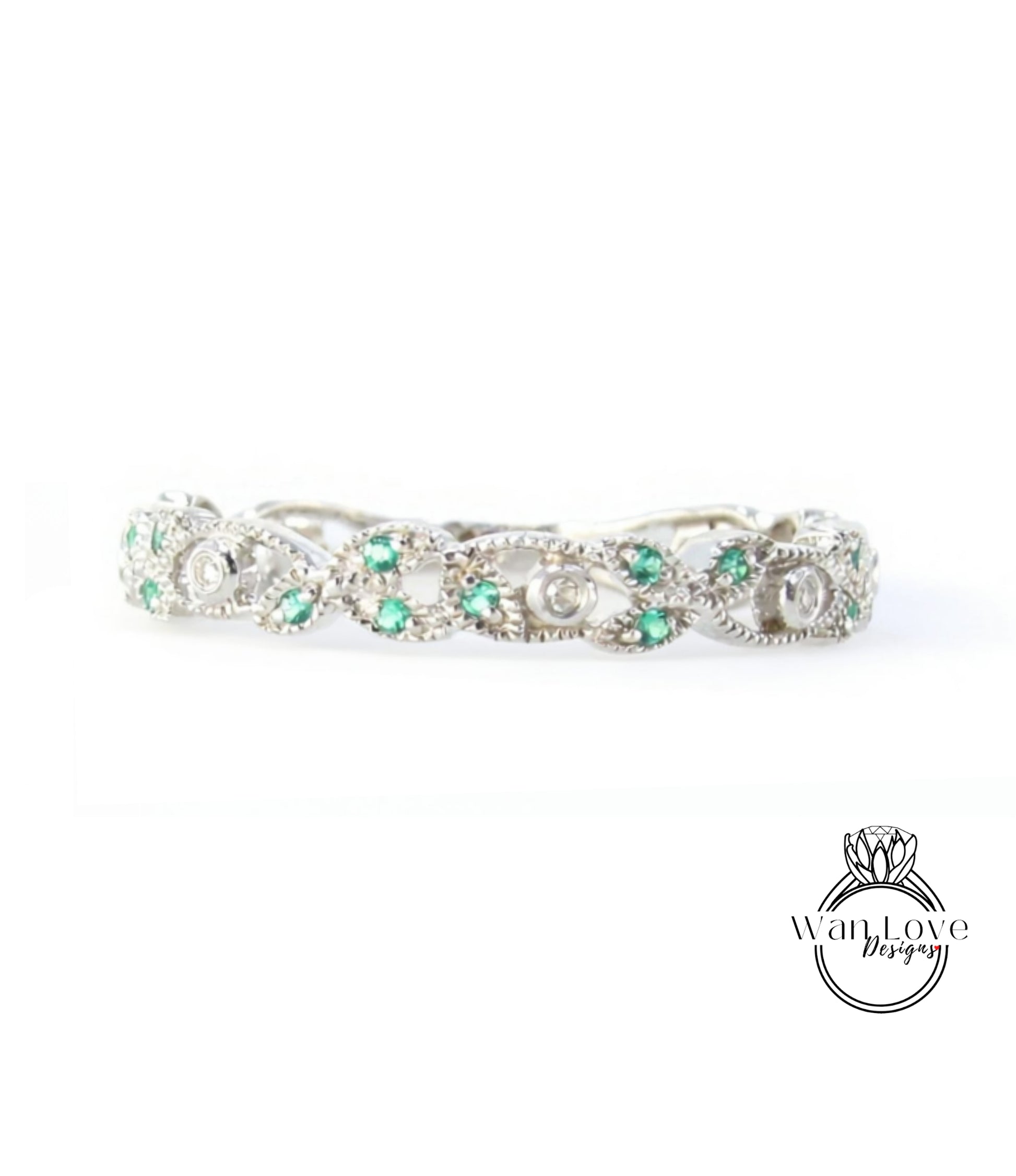 A silver ring adorned with green gemstones, including diamonds, is displayed against a white background.