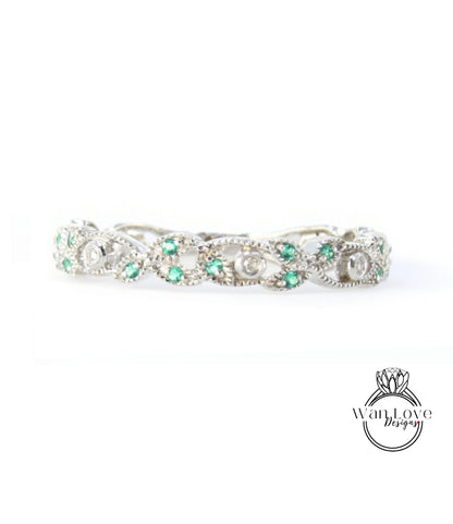 A silver ring adorned with green gemstones, including diamonds, is displayed against a white background.