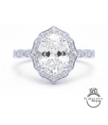 A close-up of a diamond engagement ring with a large oval-shaped diamond set in a halo of smaller diamonds.