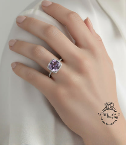 A close-up of a hand wearing a ring with a large purple gemstone, likely a diamond, on the ring finger.