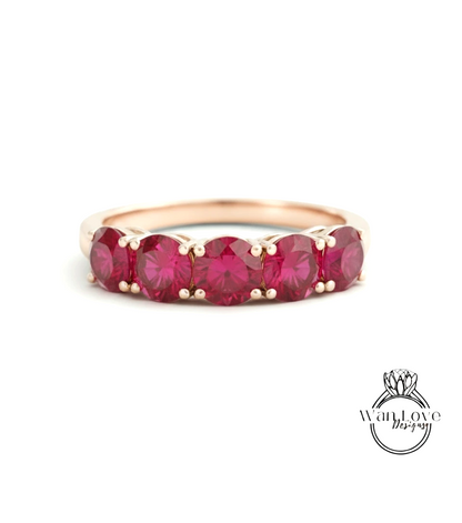 A gold ring with a row of red gemstones, likely rubies, set in the center.