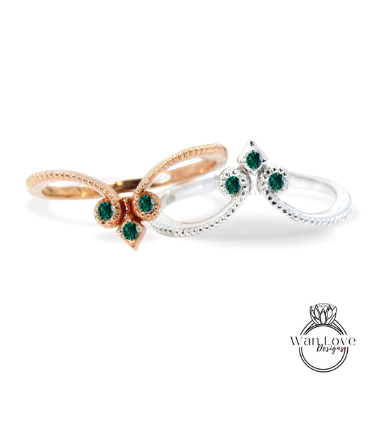 two rings with green gemstones, one silver and one gold, set against a white background.