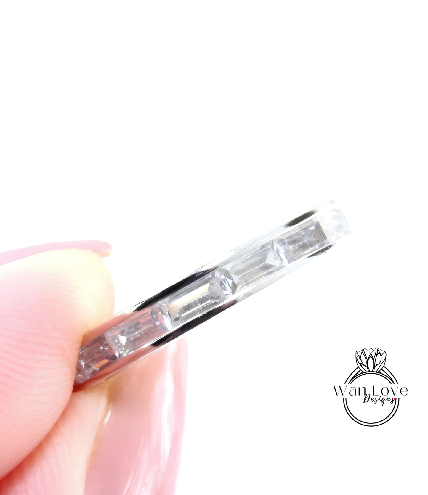 A close-up image of a person's hand holding a ring with a row of clear gemstones.