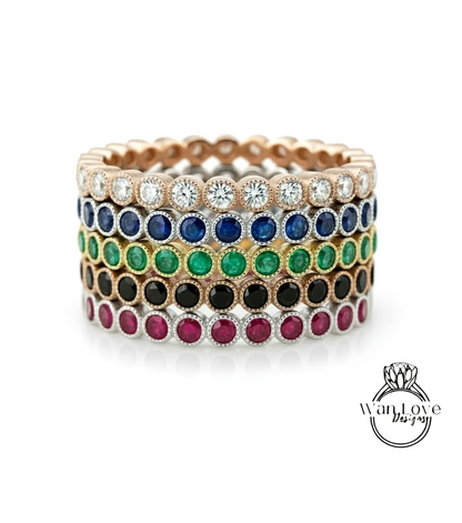 A stack of colorful rings with various gemstones, including diamonds and colored stones, set in a gold or silver band.