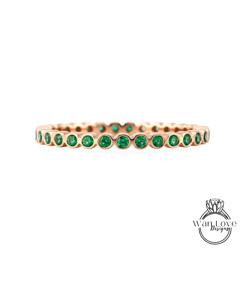 A gold-colored ring with a row of green gemstones set in it.