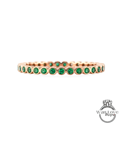 A gold-colored ring with a row of green gemstones set in it.