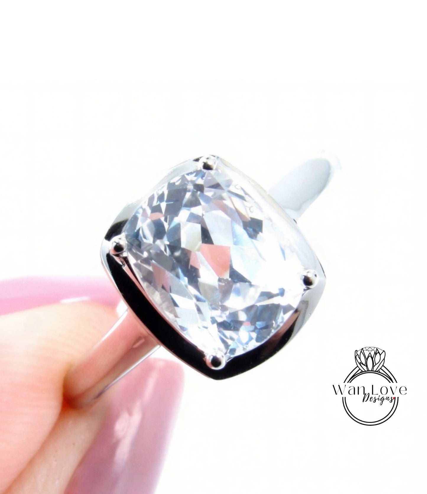 A close-up image of a person's hand holding a large, clear gemstone ring with a silver band.