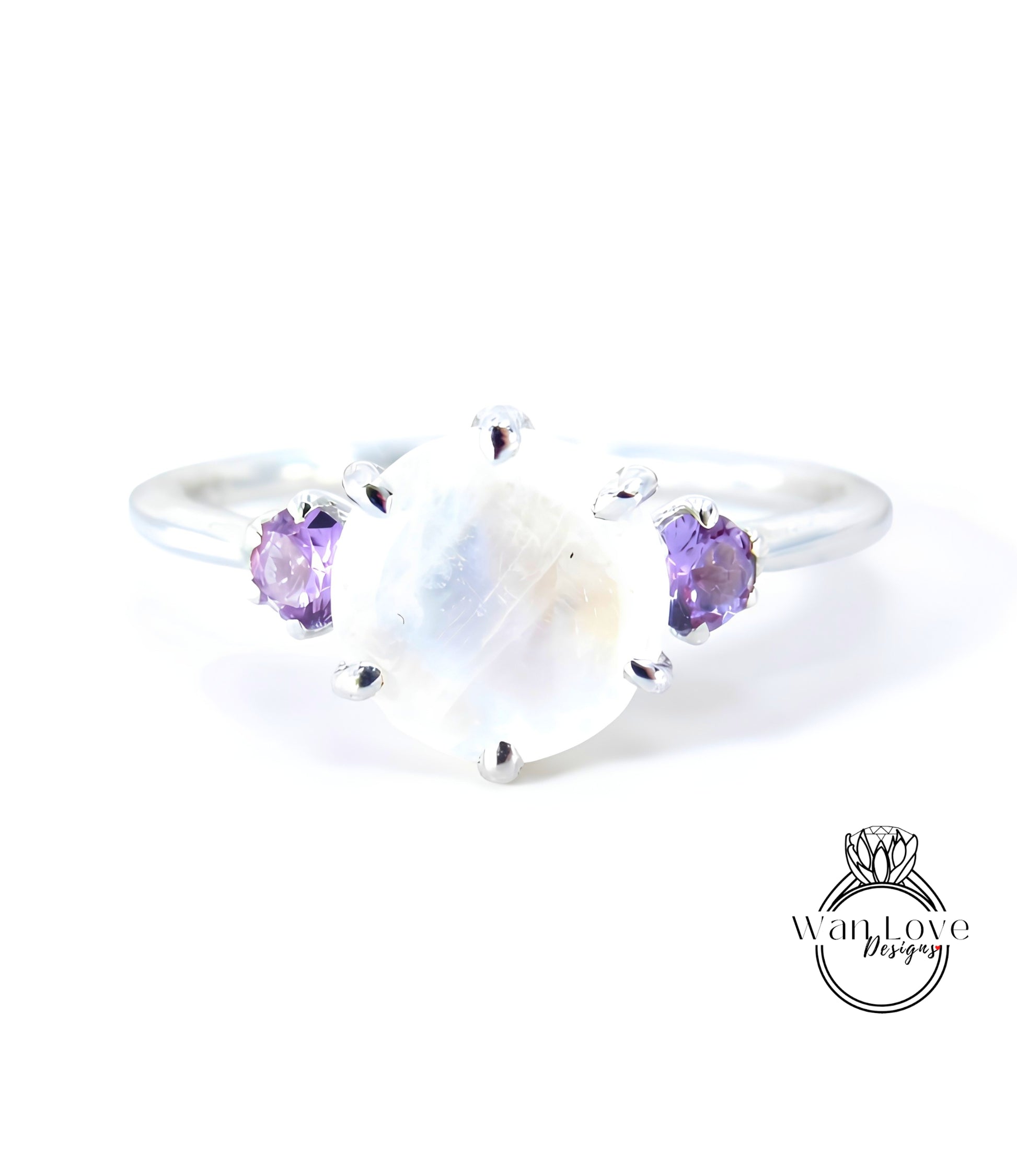 A silver ring with a large moonstone and two purple gemstones on either side.