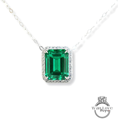 A necklace with a large, square-cut emerald gemstone surrounded by a halo of smaller diamonds.
