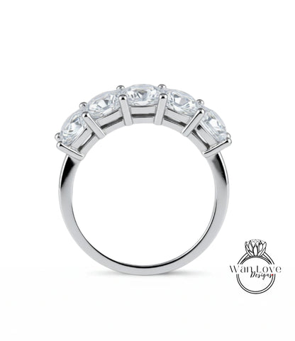 A silver ring with a row of five clear gemstones set in the band.