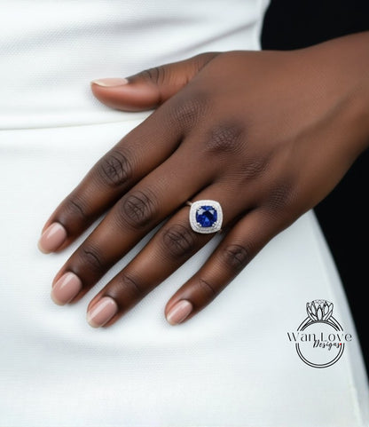 A close-up of a hand wearing a ring with a large blue gemstone.