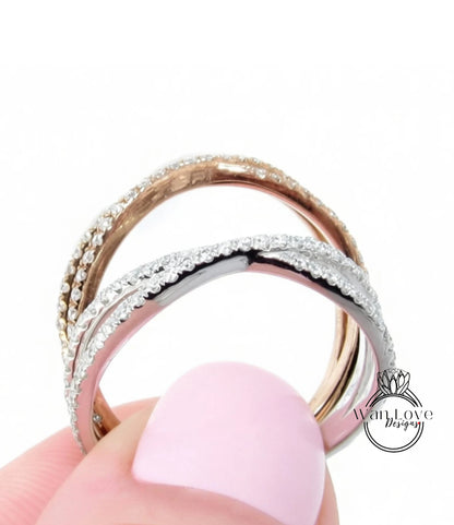 A close-up of a person's hand holding a ring with a combination of silver and gold bands adorned with sparkling diamonds.