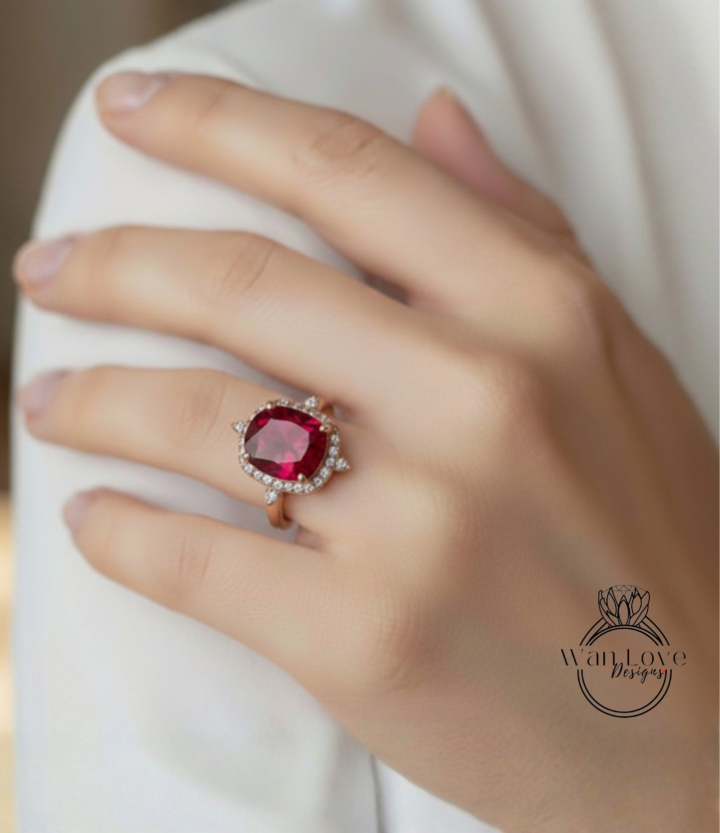 A close-up of a person's hand wearing a large, red gemstone ring with a halo of smaller diamonds around it.