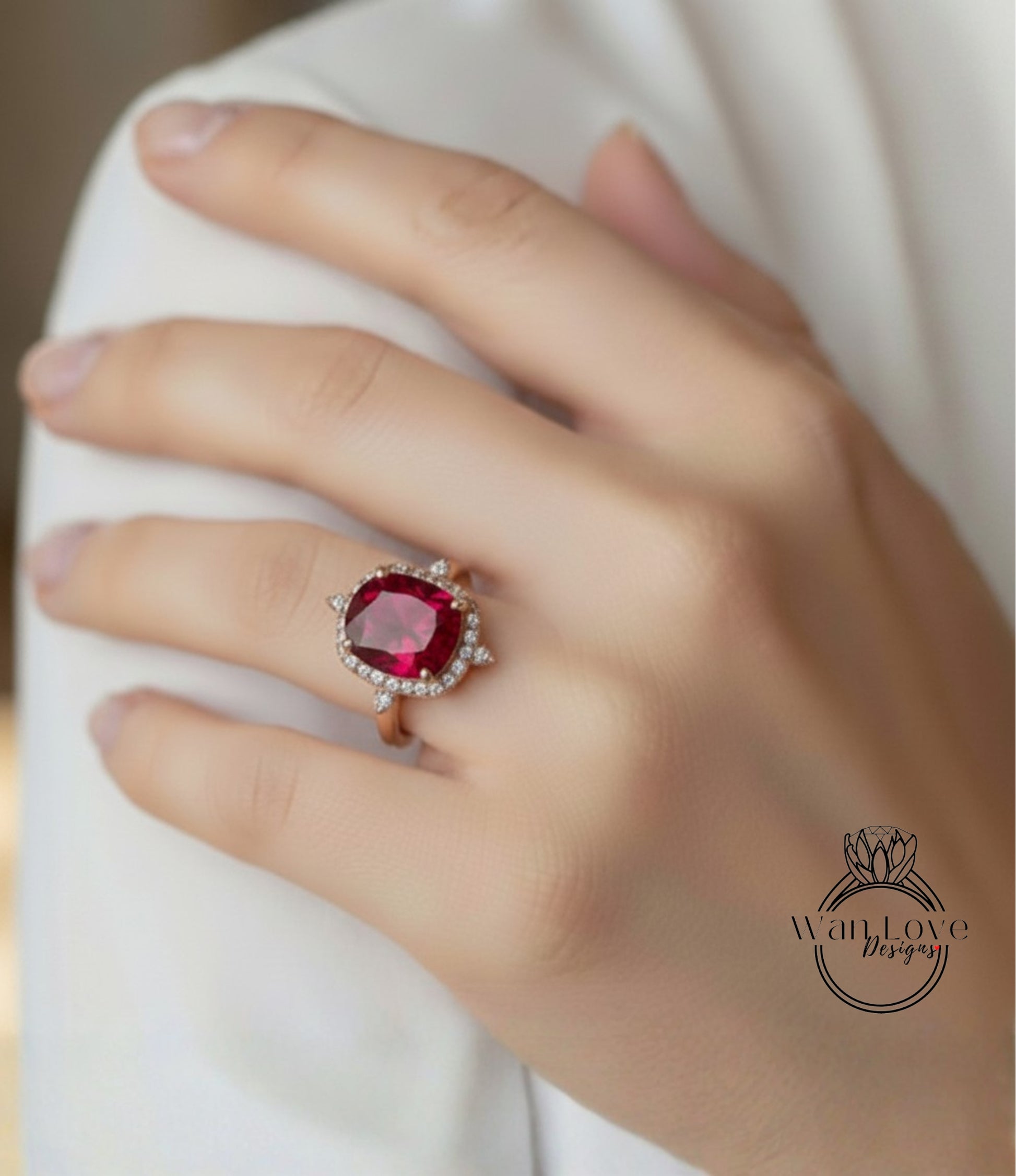 A close-up of a person's hand wearing a large, red gemstone ring with a halo of smaller diamonds around it.