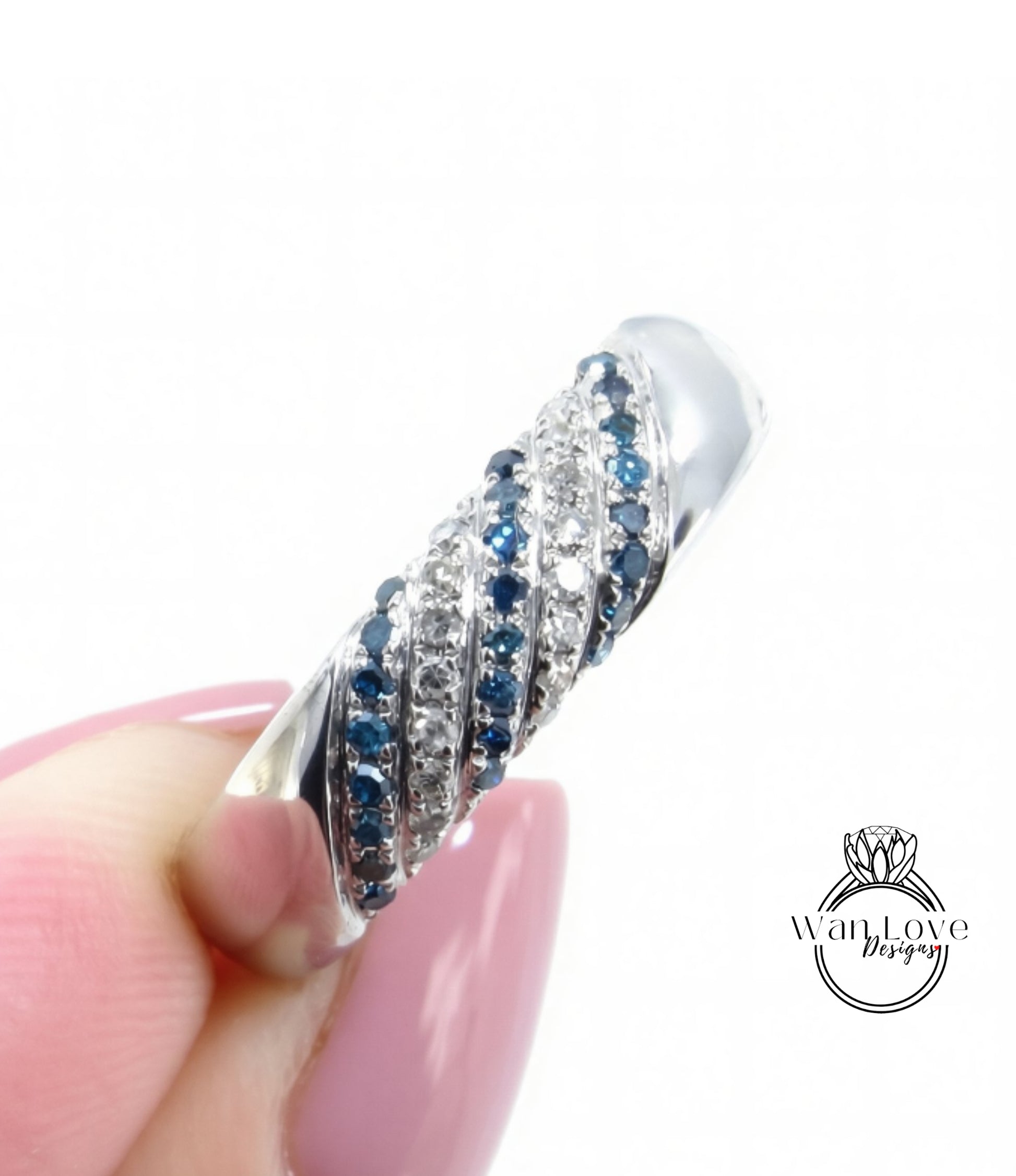 A close-up of a person's hand holding a silver ring adorned with blue and white gemstones.