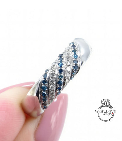 A close-up of a person's hand holding a silver ring adorned with blue and white gemstones.