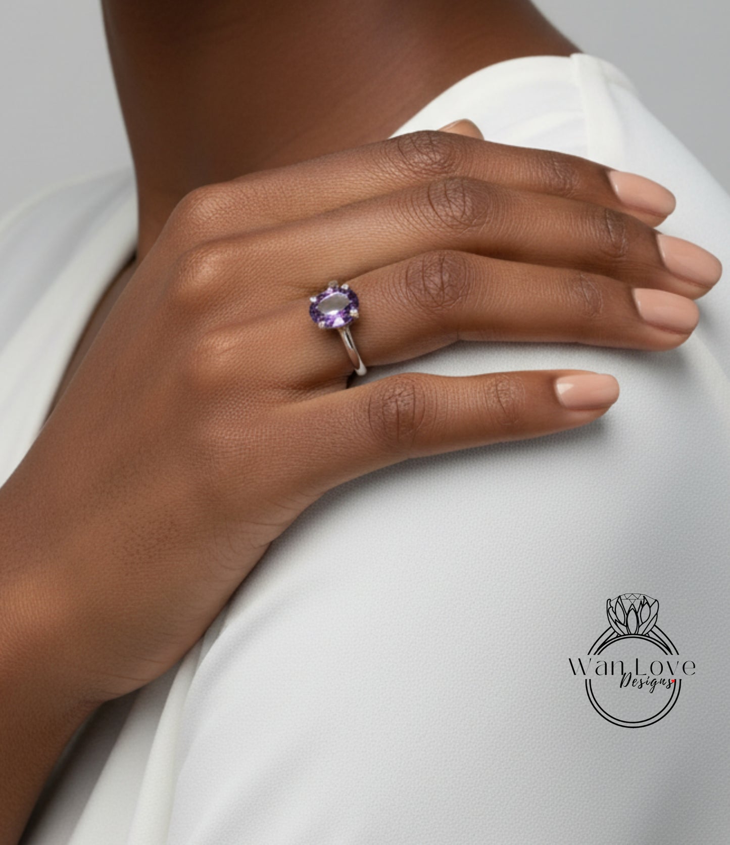 A close-up of a person's hand wearing a ring with a purple gemstone.