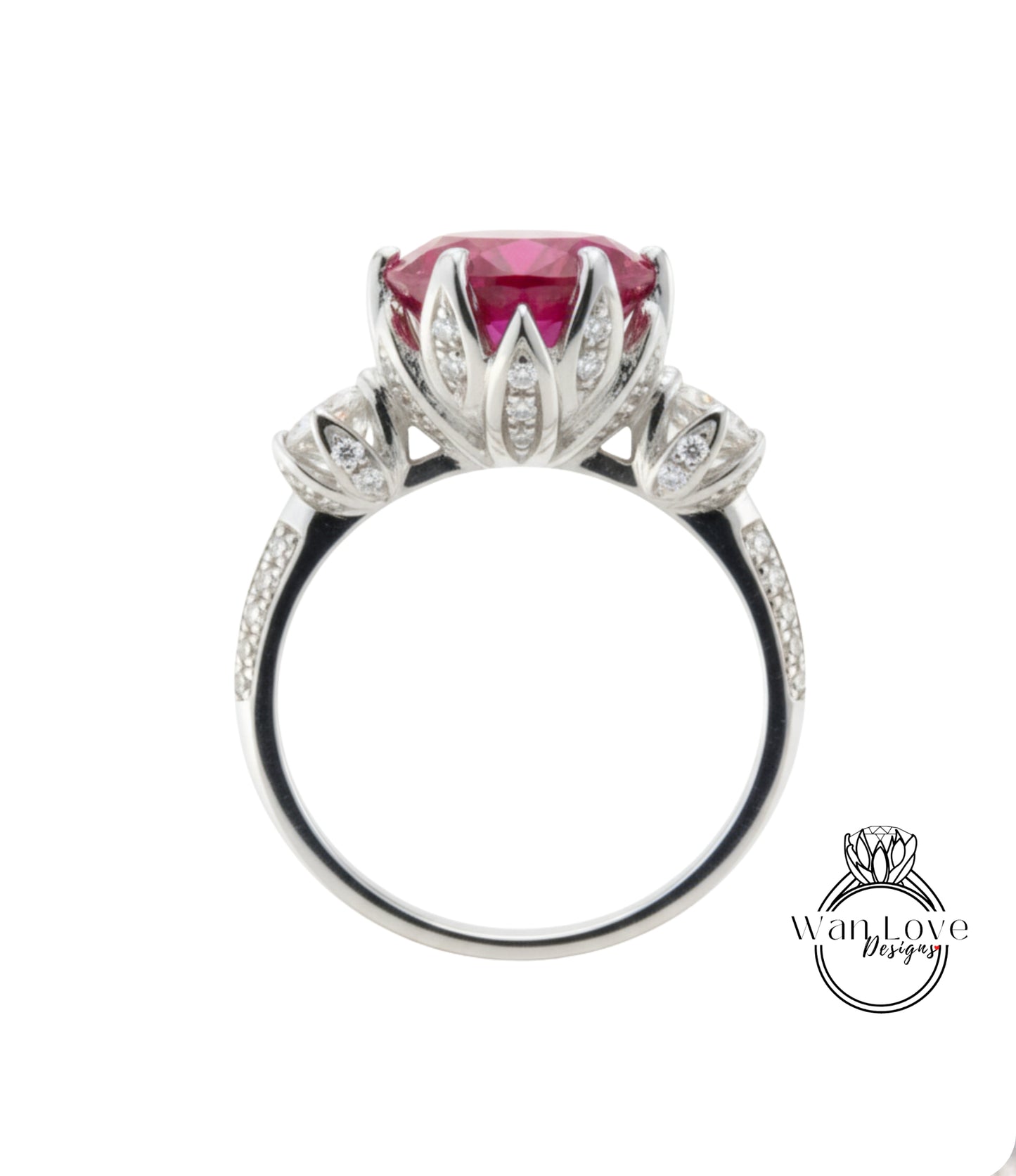 A silver ring with a large pink gemstone, likely a sapphire, at the center. The ring has a decorative design with small diamonds around the edge.
