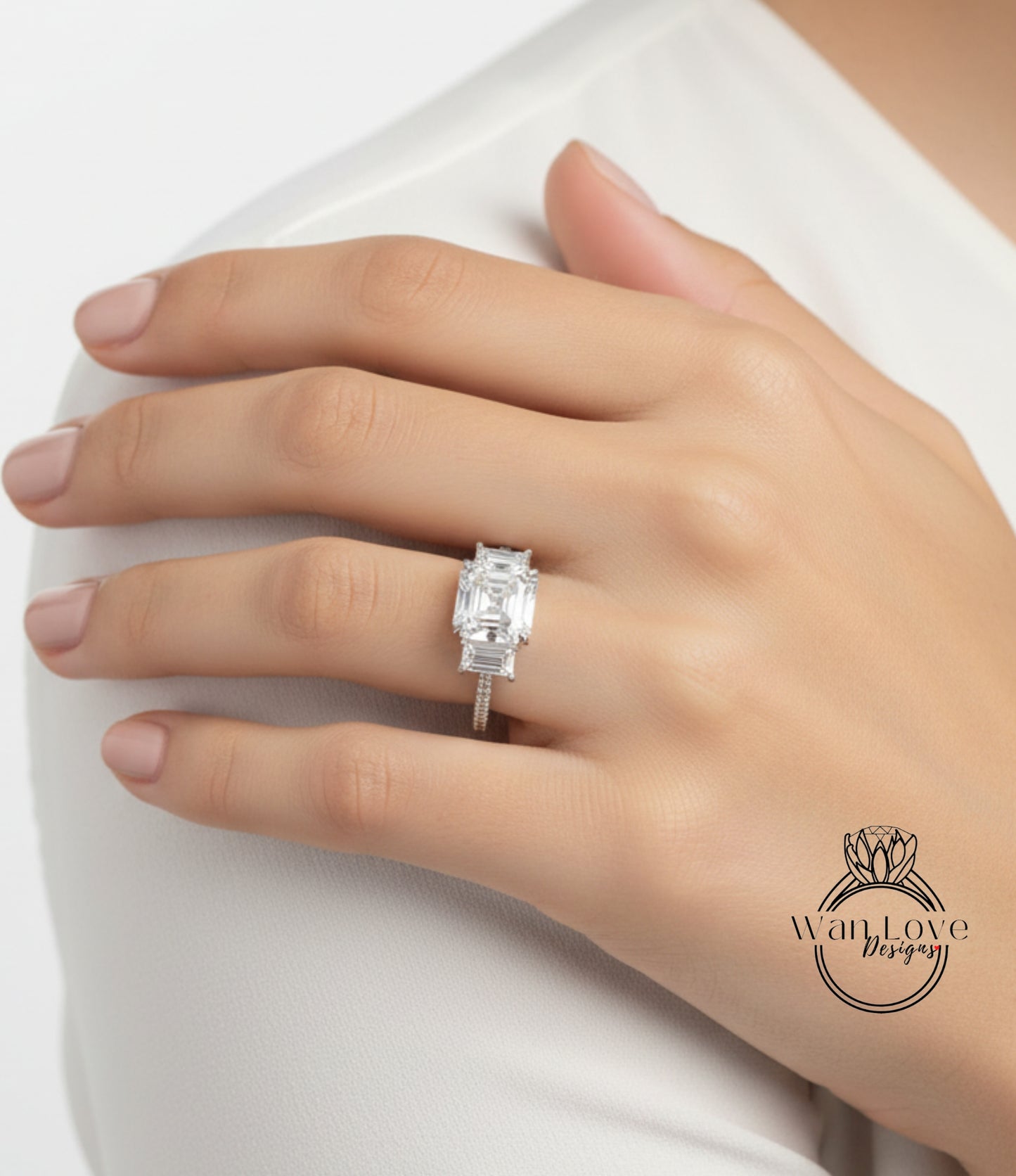 A close-up of a person's hand wearing a diamond engagement ring on the ring finger.