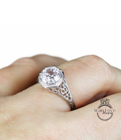 A close-up of a person's hand wearing a silver ring with a large, clear gemstone.