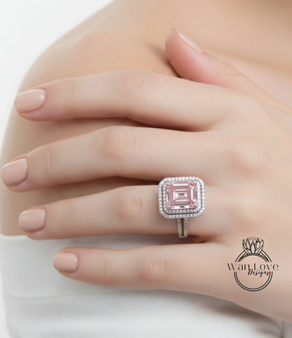 A close-up of a person's hand wearing a large, pink diamond ring with a halo of smaller diamonds around it.