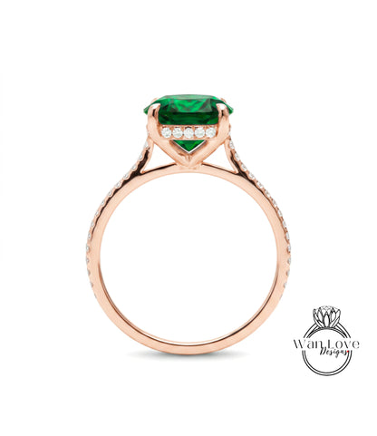 A rose gold engagement ring with a large green gemstone and small diamonds set in the band.