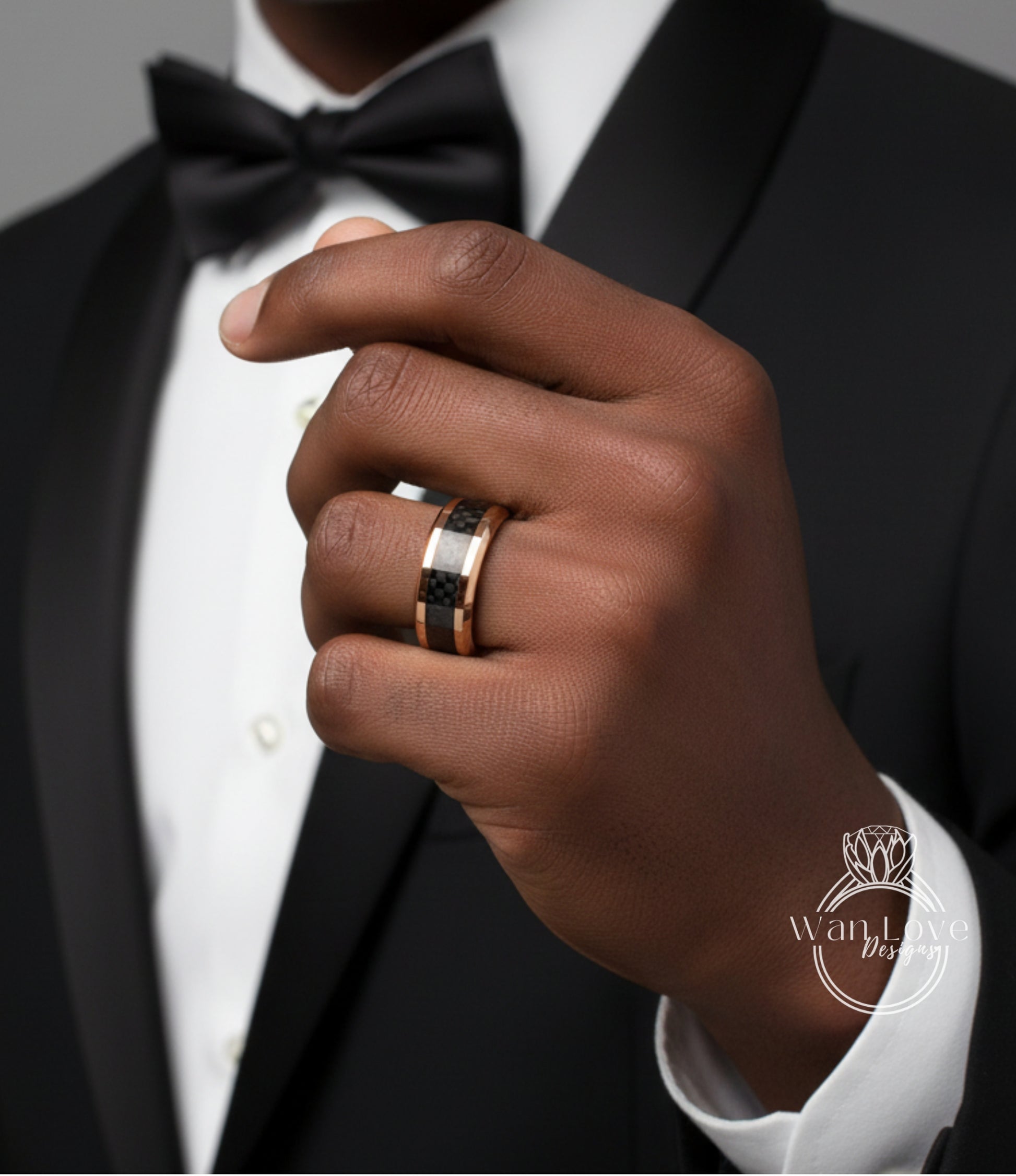 A close-up of a person's hand wearing a black tuxedo and a gold ring on the ring finger.