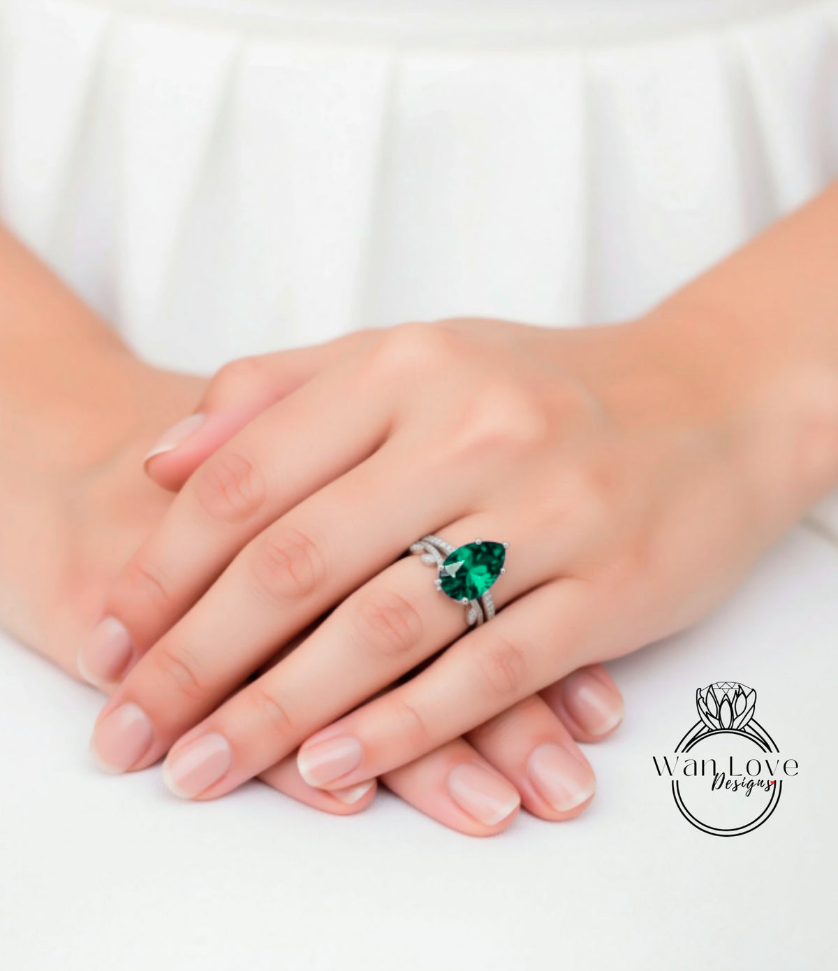 A close-up image of a person's hands wearing a ring with a large, vibrant green gemstone.