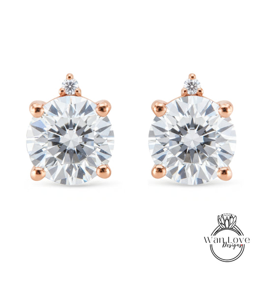 two diamond earrings with a large, clear gemstone set in a rose gold-colored metal.
