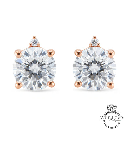 two diamond earrings with a large, clear gemstone set in a rose gold-colored metal.