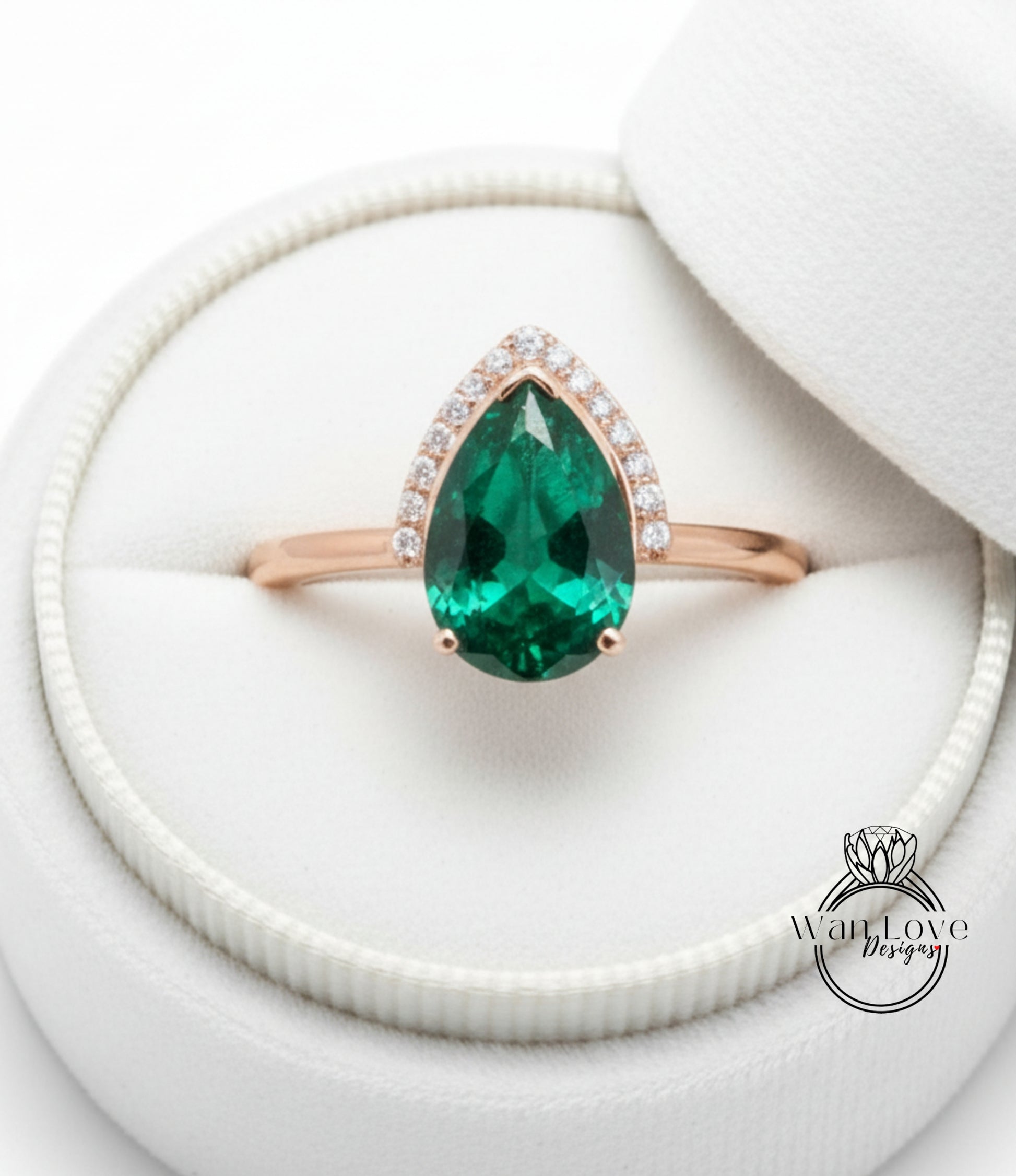 A gold ring with a large, green gemstone set in the center, placed in a white jewelry box.