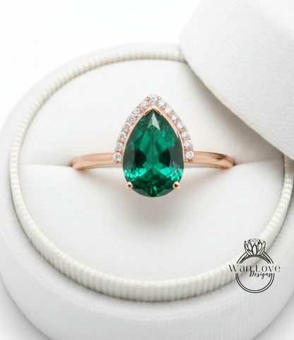 A gold ring with a large, green gemstone set in the center, placed in a white jewelry box.