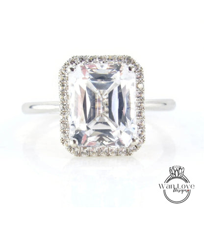 A large, clear gemstone ring with a halo of smaller diamonds around the center stone.