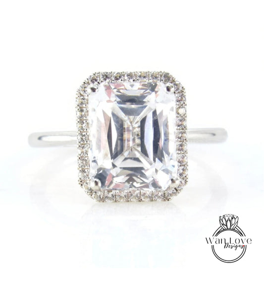 A large, clear gemstone ring with a halo of smaller diamonds around the center stone.