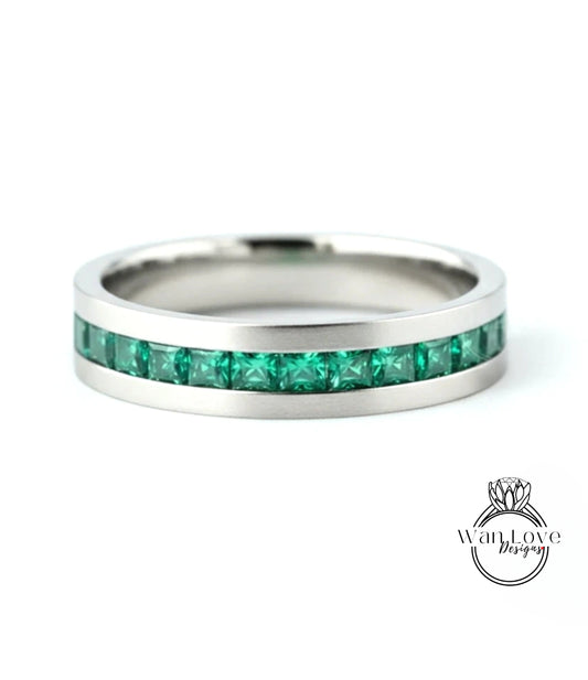 A silver band ring with a row of green gemstones embedded in it.
