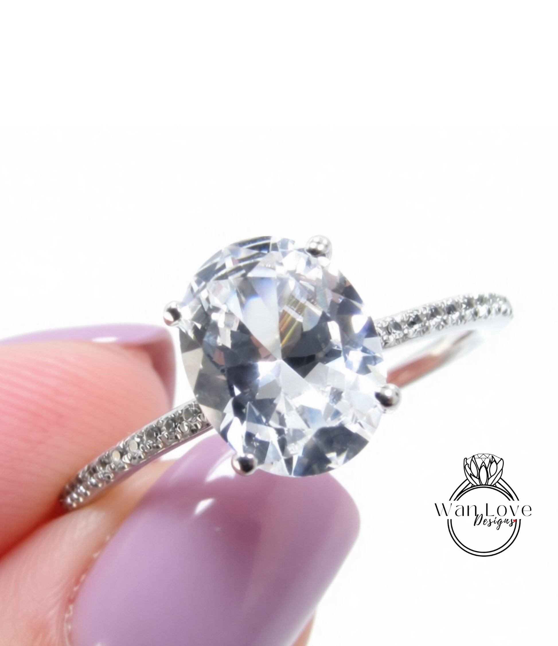 A close-up image of a diamond engagement ring being held in someone's hand, with a large oval-shaped diamond set in a silver band.