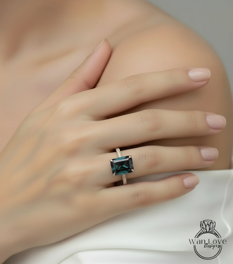 A close-up of a person's hand wearing a ring with a large, dark green gemstone.