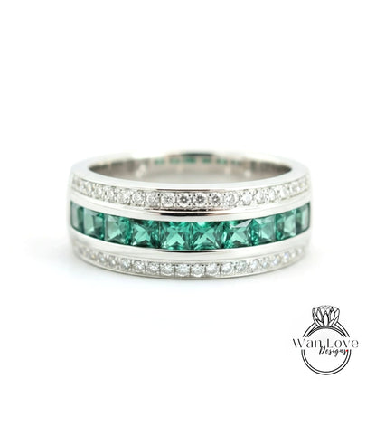 A silver ring with a row of green gemstones, likely diamonds, set in a band.