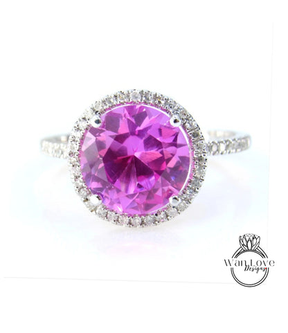 A large, round, pink gemstone ring with a halo of smaller diamonds around the center.