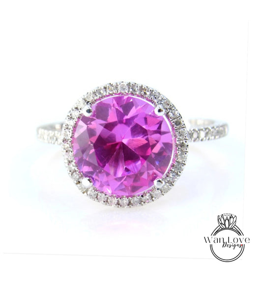 A large, round, pink gemstone ring with a halo of smaller diamonds around the center.