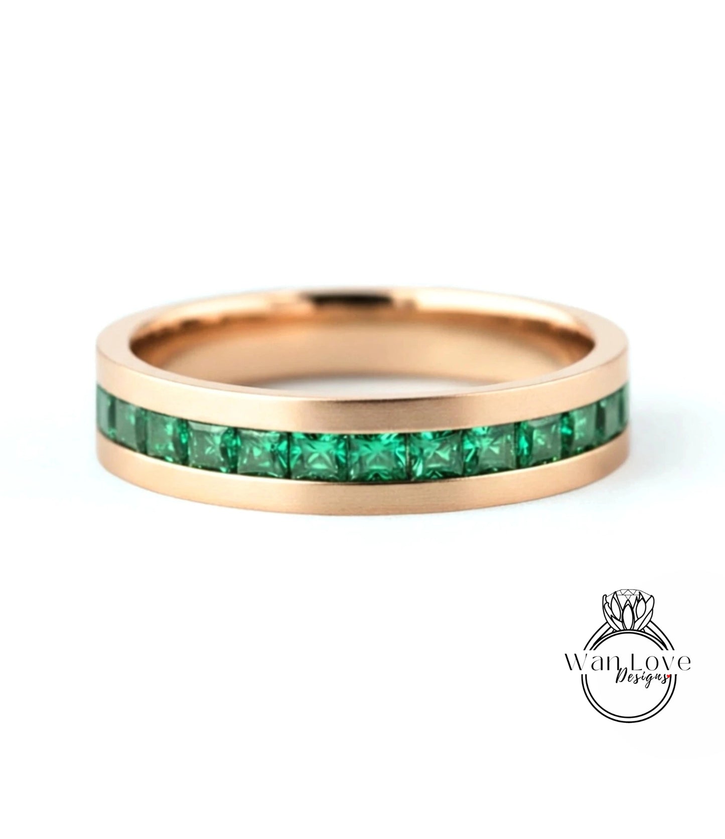 A gold-colored ring with a row of green gemstones embedded in the band.