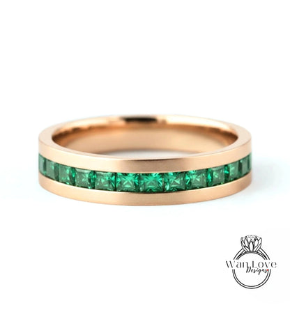 A gold-colored ring with a row of green gemstones embedded in the band.