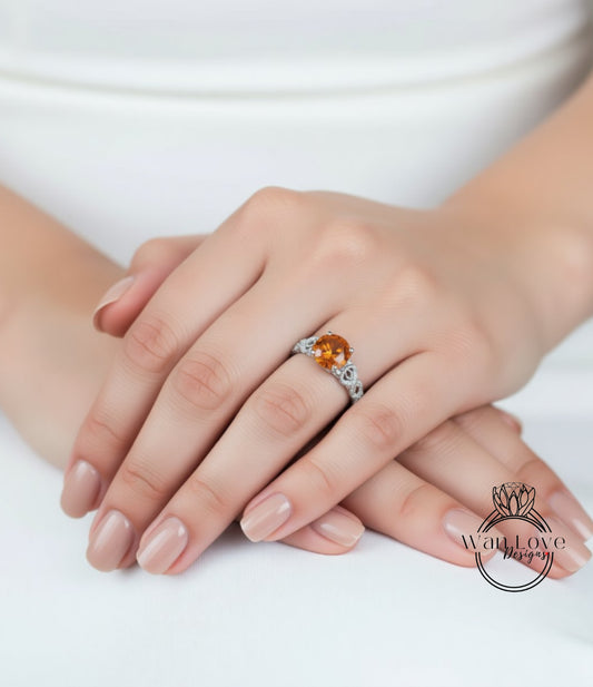 A close-up of a person's hand wearing a ring with an orange gemstone.